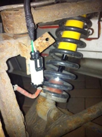 The finished repair: the loom running down to a new black connector joined to the cream sensor plug, beside the spring