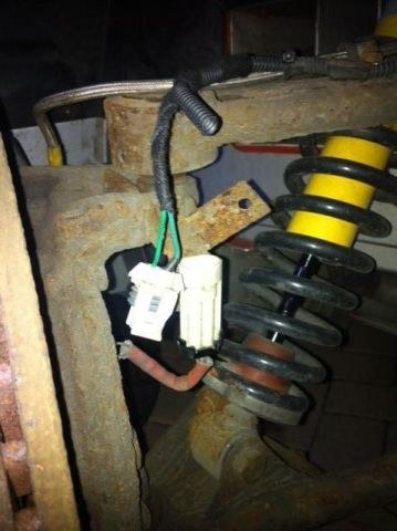The wiring loom running down beside the suspension to a cream plastic connector at the hub, with green and white wires showing at the connector