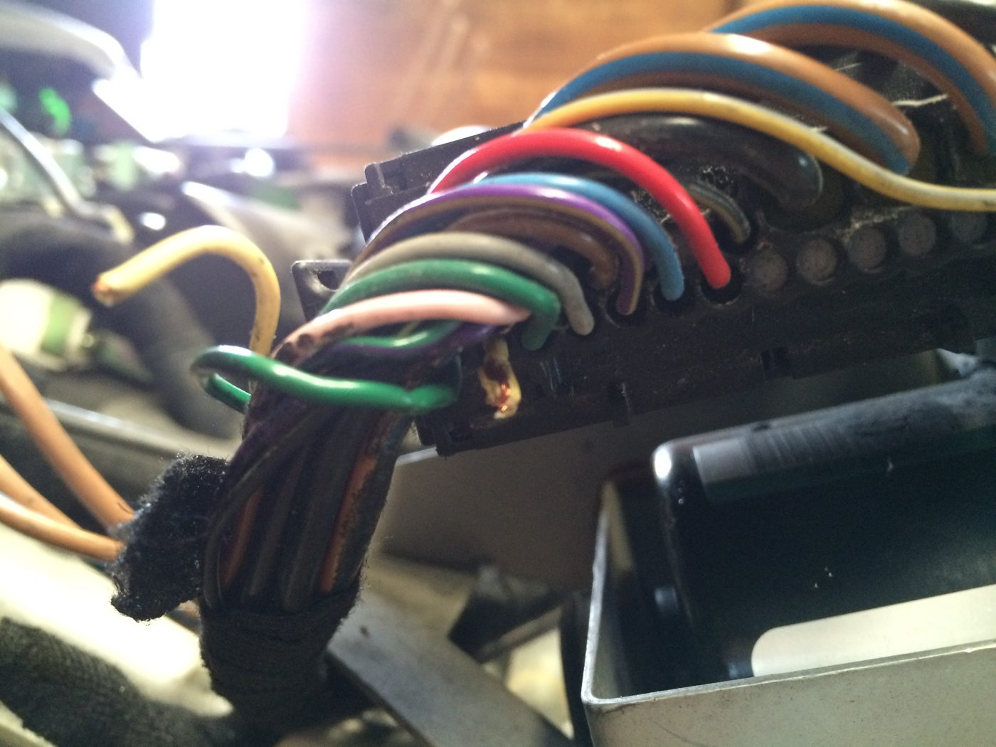 The ABS module’s plug with a bundle of coloured wires, including green, pink, grey and purple wires, and a yellow wire loose on the left