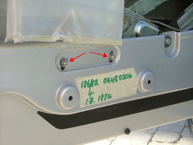 Two bolts in a slot on the inner door panel, marked with red arrows