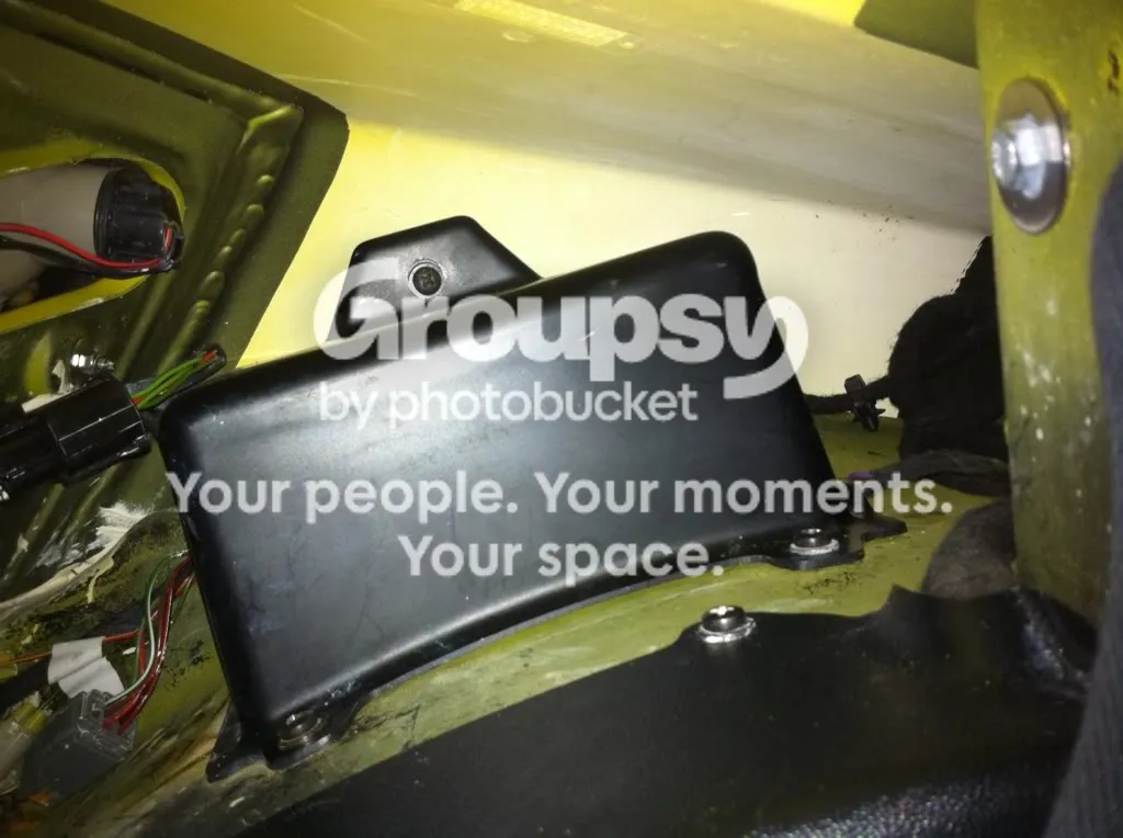 A black plastic cover over the backup battery in the boot, above the nearside wheel arch, with a screw on top and two screws into the arch