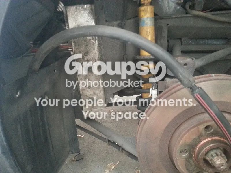 A black hose with a red stripe running past a rear shock and brake disc, joined to the old hose