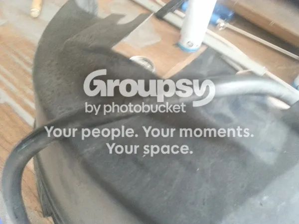 A black hose with a kink lying over the edge of a wheel liner on a bench