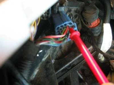 A blue connector block with a bundle of coloured wires and a red meter probe pushed into it