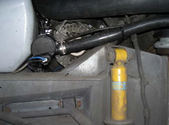 A black hose and a pump with blue wires behind the rear wheel arch, mounted on the chassis