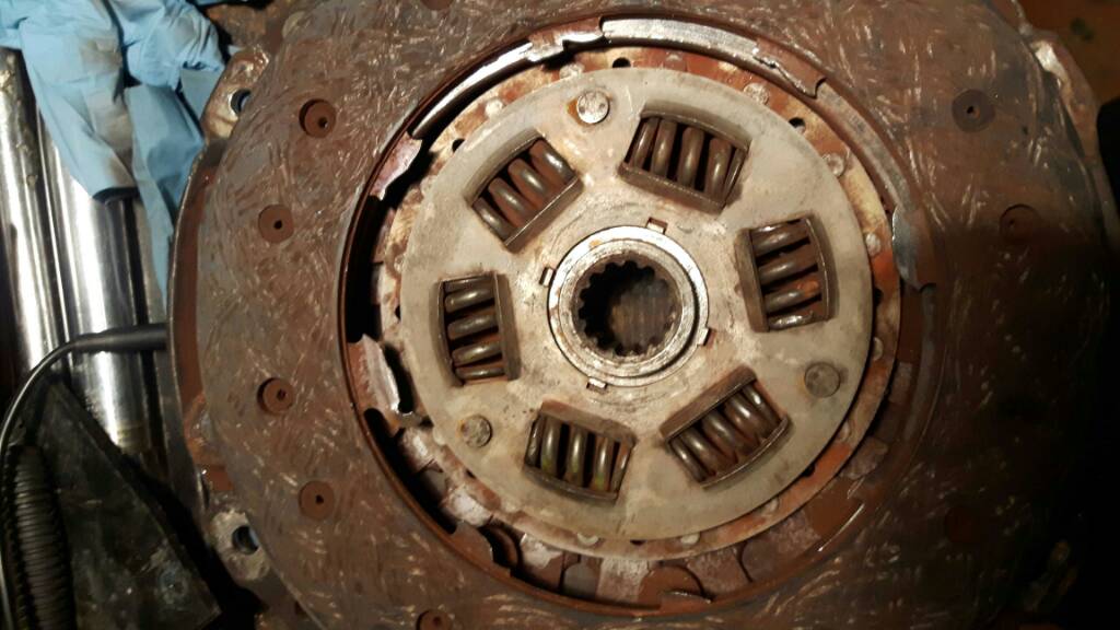 A failed clutch friction plate with the damper springs in the hub, rust-coloured, and the metal cracked around the springs