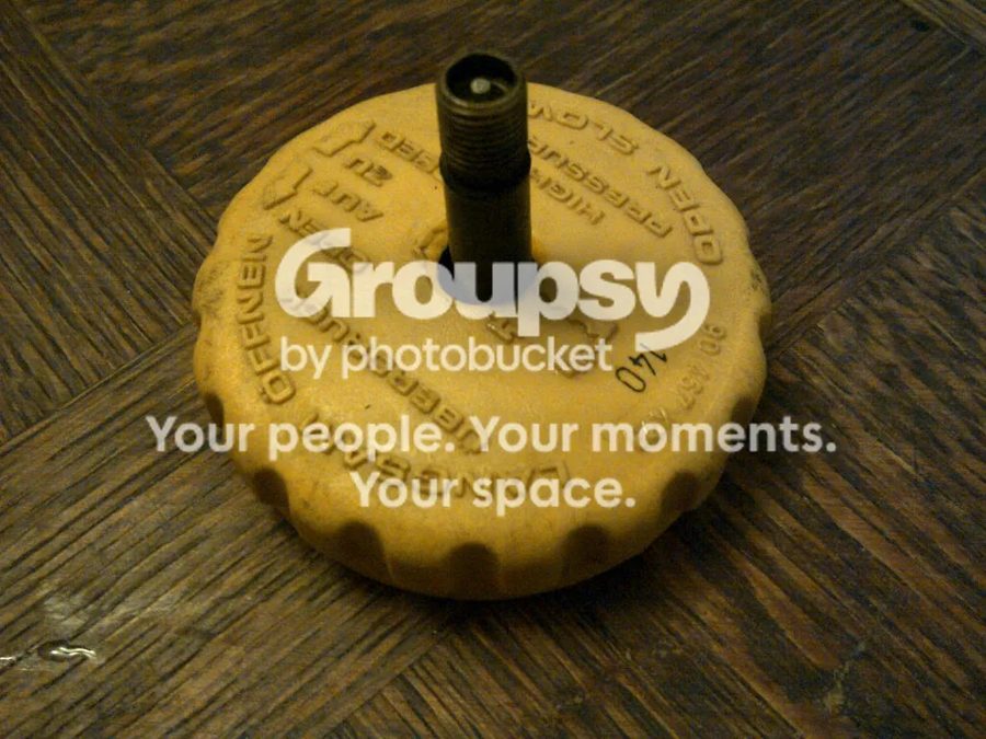 A yellow coolant cap with a tyre valve fitted through the top