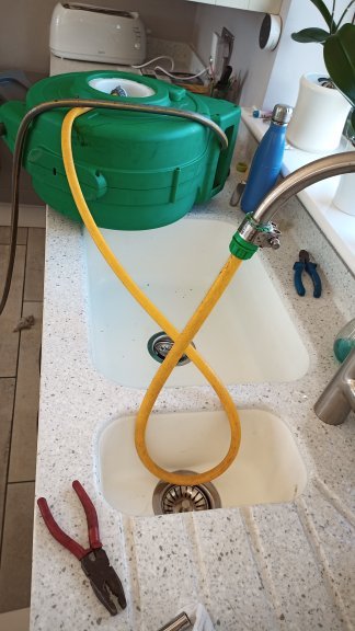 A hose attached to a kitchen tap over a sink