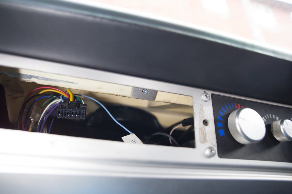 A screw visible through the head unit opening, with the rivet hole for the dash plate near the heater controls