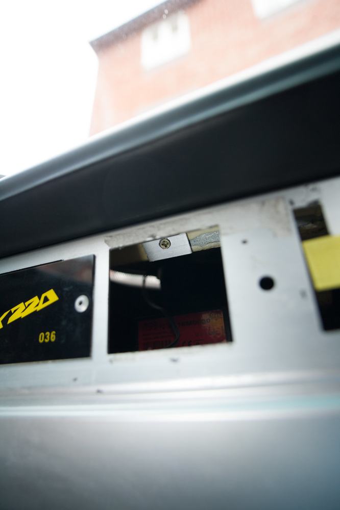 The small square hole beside the VX220 plate where a screw sits