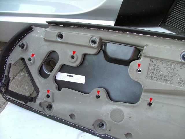 The back of a door card with six red arrows on the clip positions