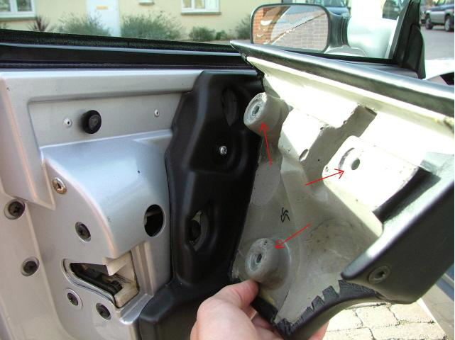 The back of the door panel at the handle guard, with red arrows on the two plastic posts and another fixing