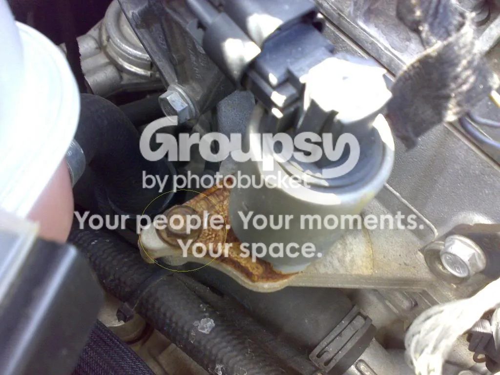 The EGR valve on the engine with the rusty bracket and one mounting bolt circled