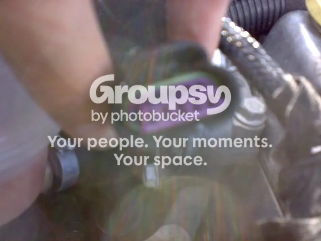 A blurred close-up of a hand pressing on the EGR valve electrical connector, purple inside