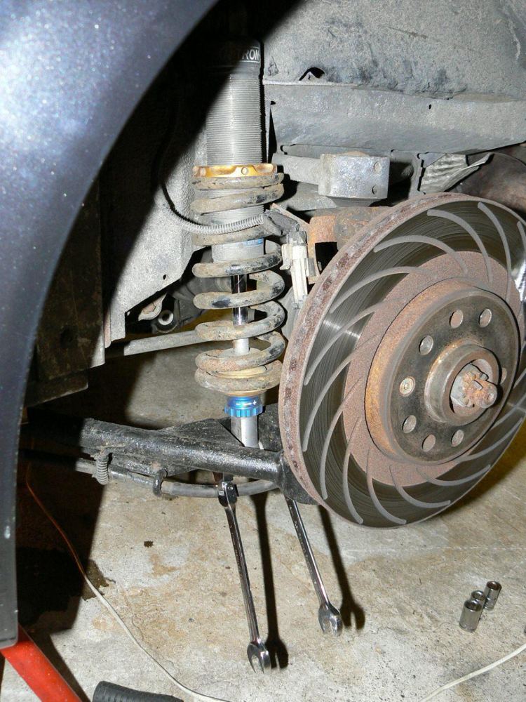 A rear wheel arch with the coil-over removed and the lower wishbone hanging