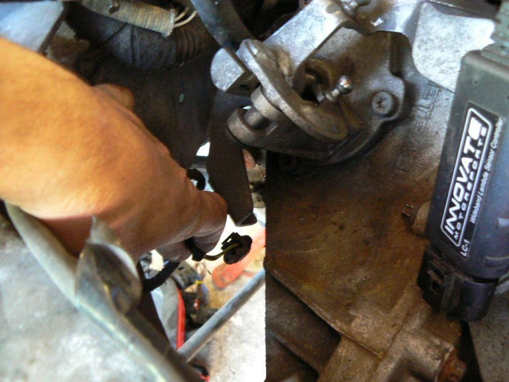 A hand prising a selector cable off the gearbox turret