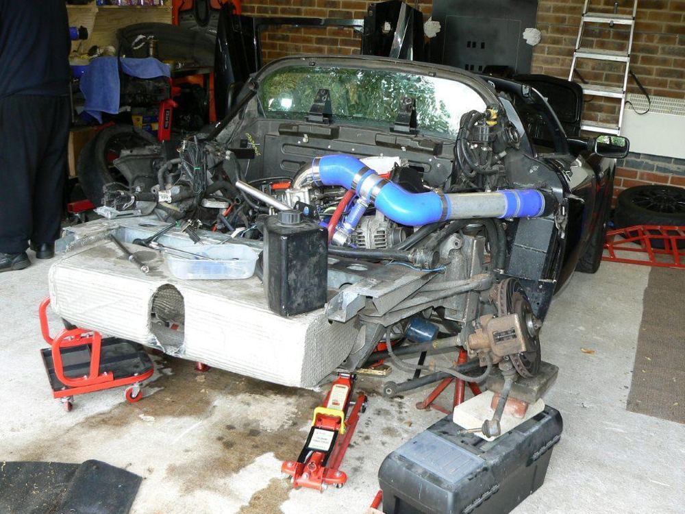 The rear of the car with the clam off and the engine supported on jacks
