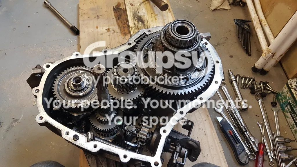 The opened gearbox case from above showing the gears and the differential, with tools laid out beside it
