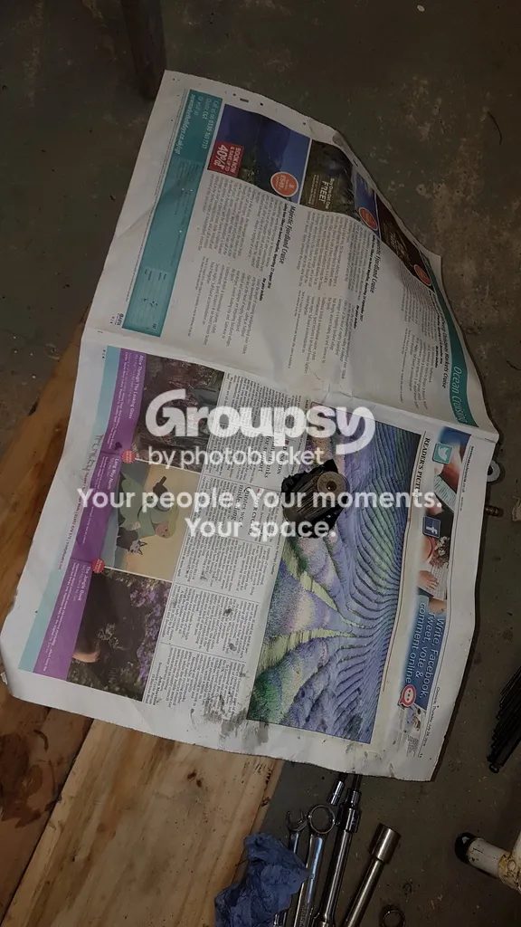 Newspaper spread over a bench next to tools and a rag