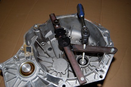 A home-made metal tool with a blue-handled screw fitted across the inside of a bell housing