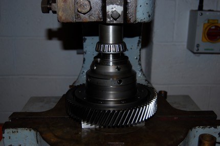 The LSD standing on its crown wheel in a press with a bearing being pressed onto the hub