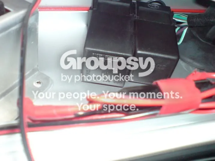 Two black relays side by side, mounted on a bracket under the dash, with red and green wires nearby