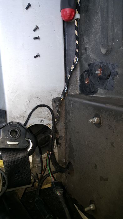 Seat belt reel area with four screws laid out and a large bolt below