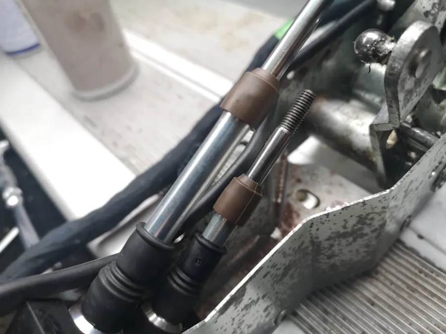 Two gear cables in the cabin with brown rubber seals where the inner cable enters the outer
