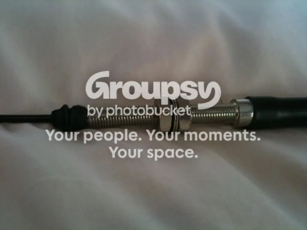 A close-up of the threaded cable adjuster with two nuts and washers and a spring