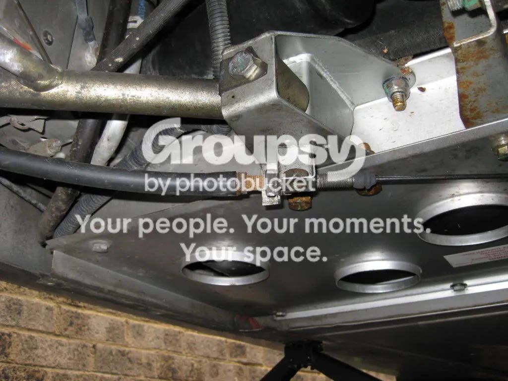 The crescent bracket under the car with the cable adjuster and bolts fitted