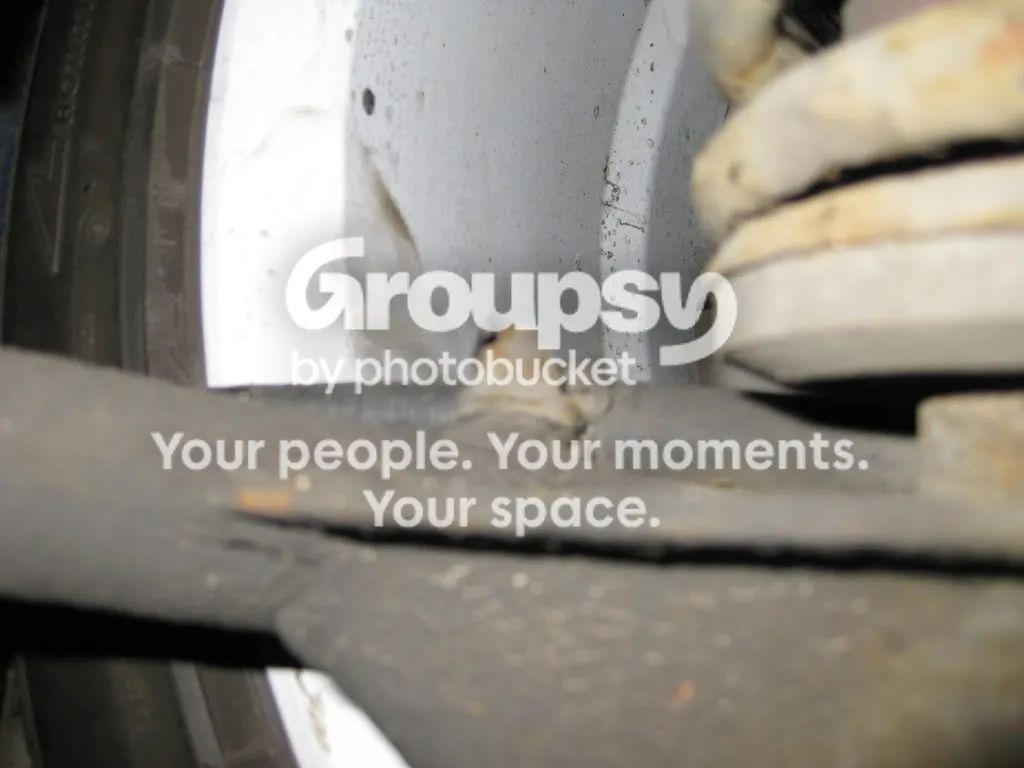 A P-clip holding the handbrake cable to the underside of the rear wishbone, near the spring