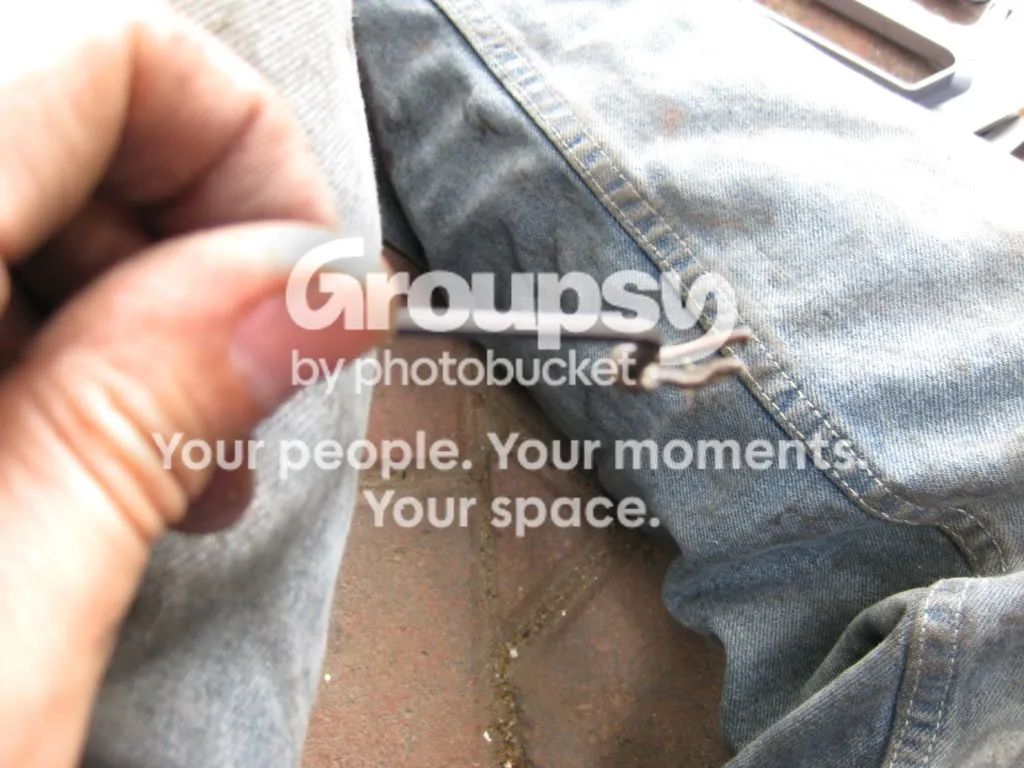 A hand holding a small R-pin pulled out of the crescent link