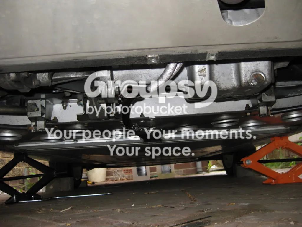 The underside of the car with the rear undertray removed and a scissor jack either side