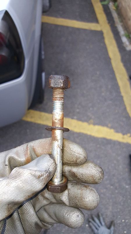 The toe link bolt held in a gloved hand