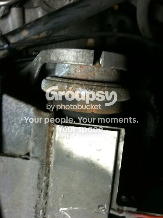 The off-side engine mount seen from underneath, with a rusty rubber mount below the bracket