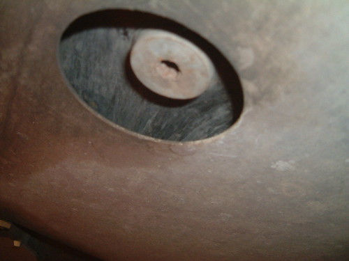 Looking up through a round cut-out in the undertray at a flat disc with a small hole in its centre