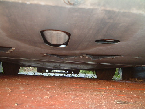 The underside of a car showing a flat undertray with two oval cut-outs