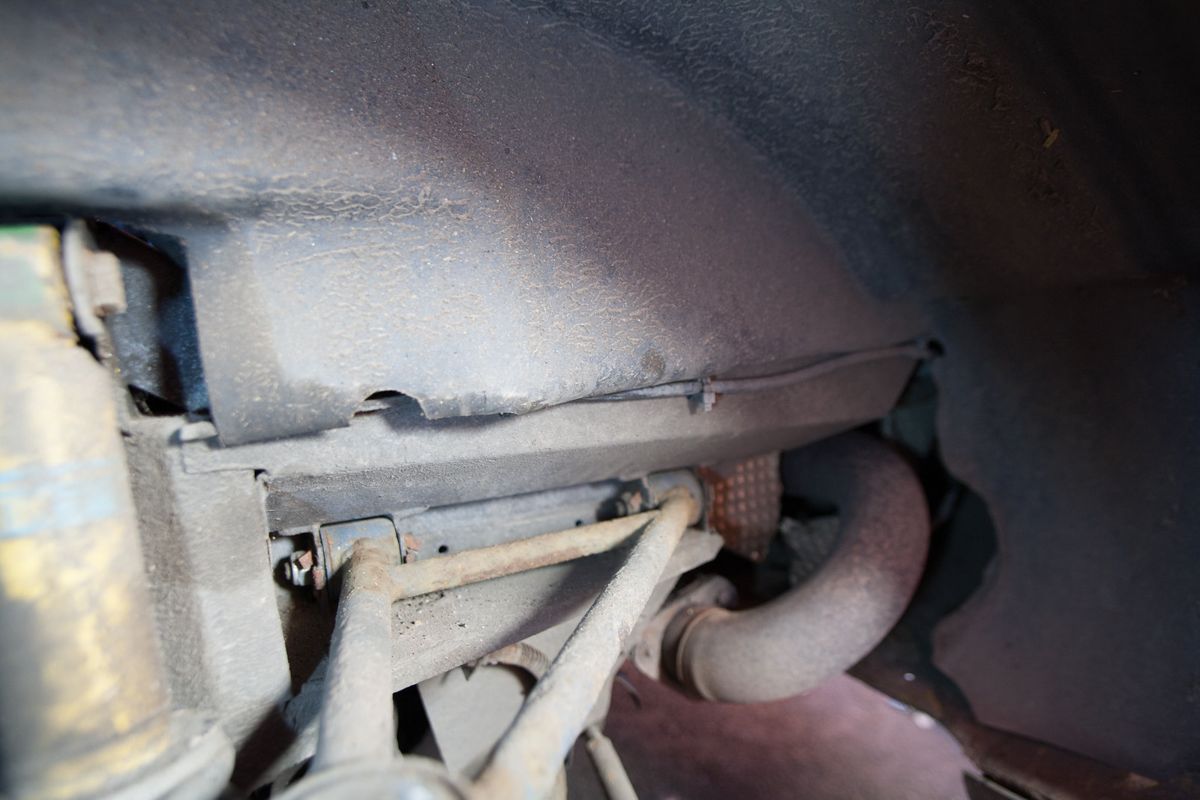 The rear wheel arch with the liner removed and a thin wiring loom running along the top edge