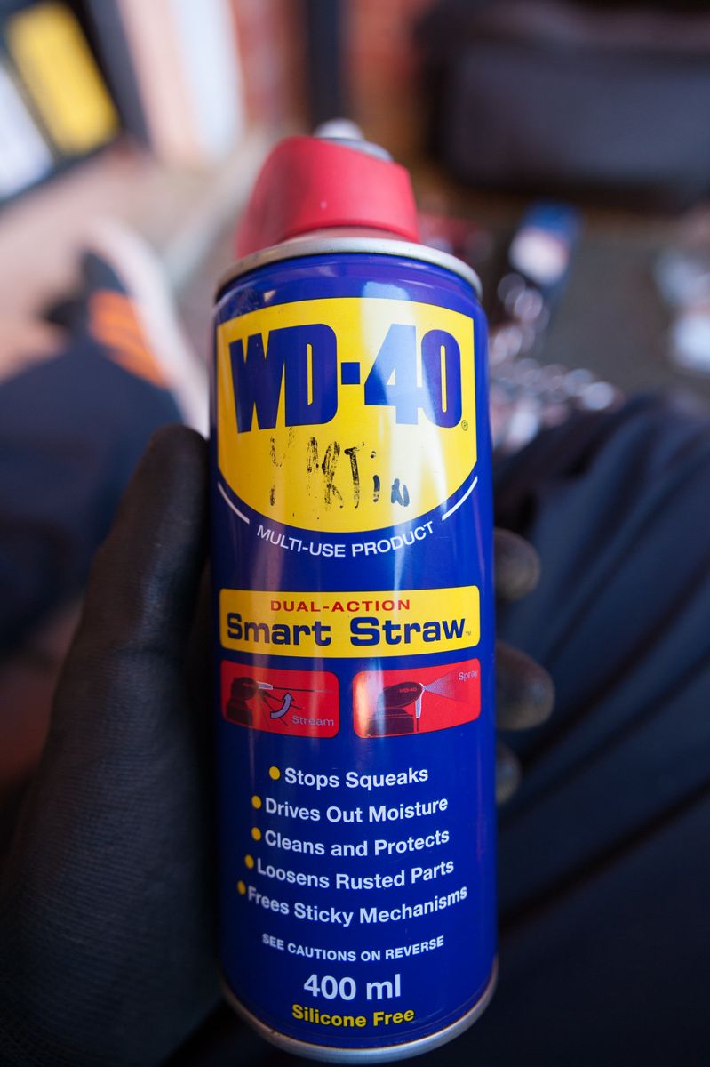 A gloved hand holding a can of WD-40 Smart Straw