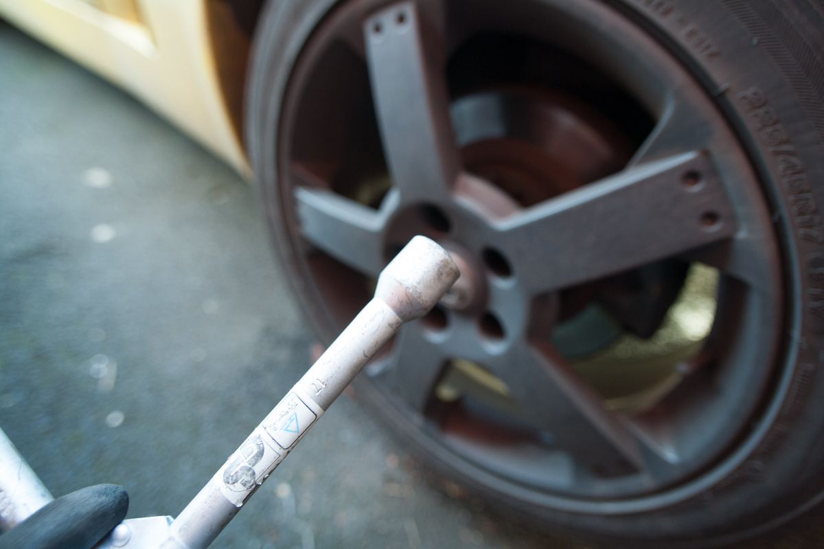 A wheel brace on one of the wheel nuts of a dark alloy wheel