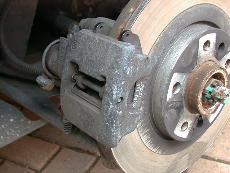 A rear brake caliper on its disc, seen from the side, with the pad pin visible at the front