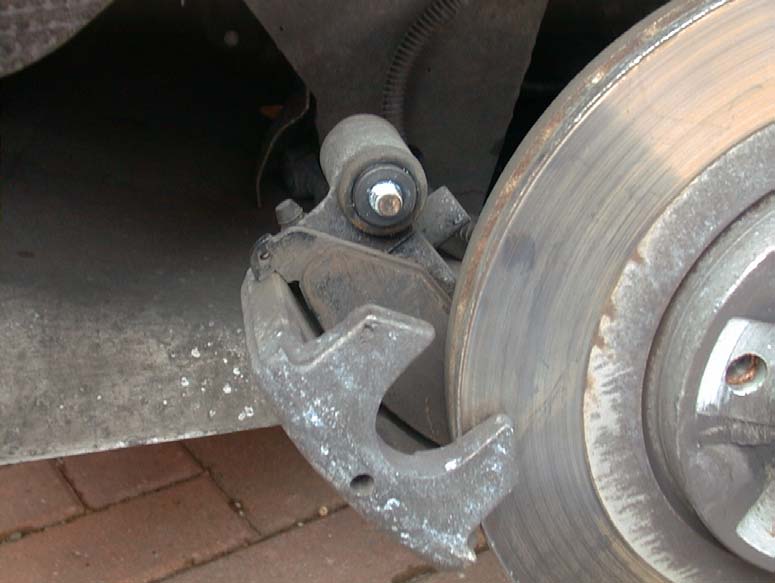 The rear caliper leaned back on its mount, away from the disc, with a pad visible