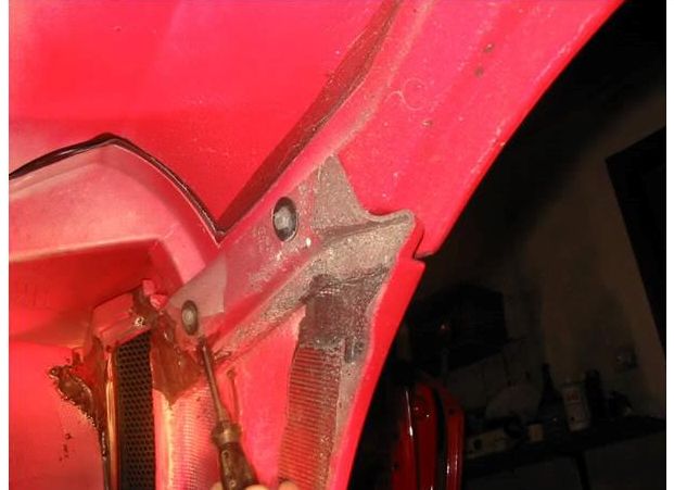 A bolt inside the wheel well behind the side vent