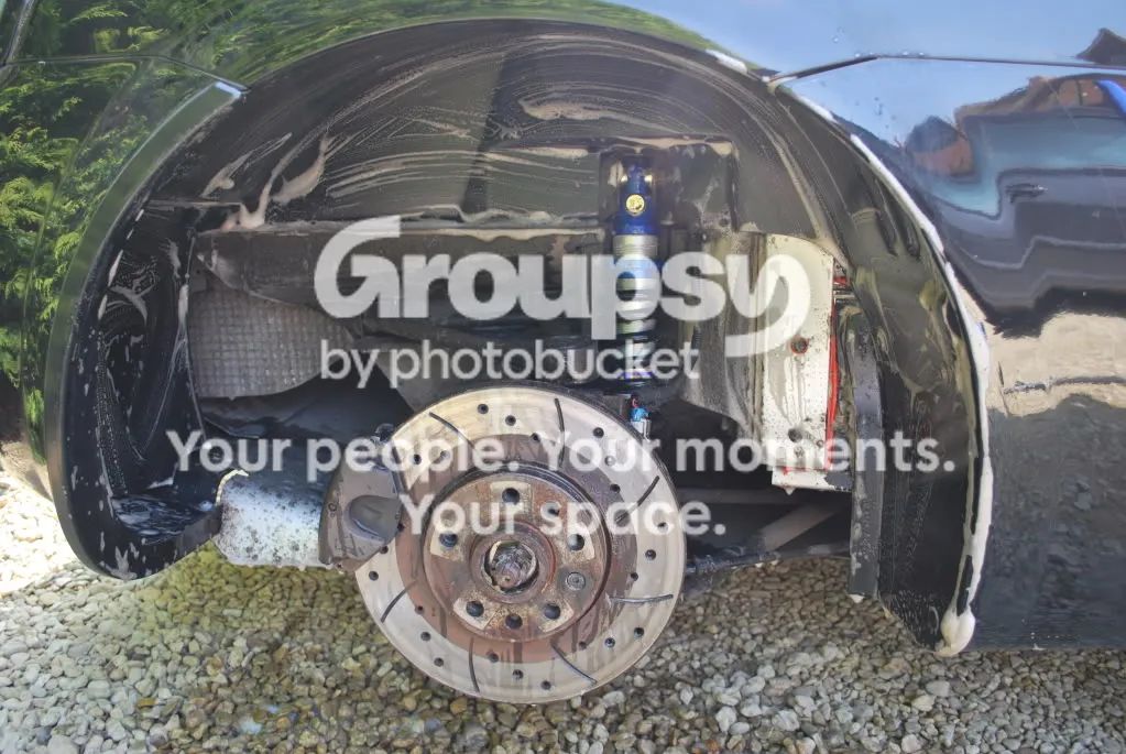 A rear wheel arch with the liner removed and the new blue shock fitted, with the disc on the hub