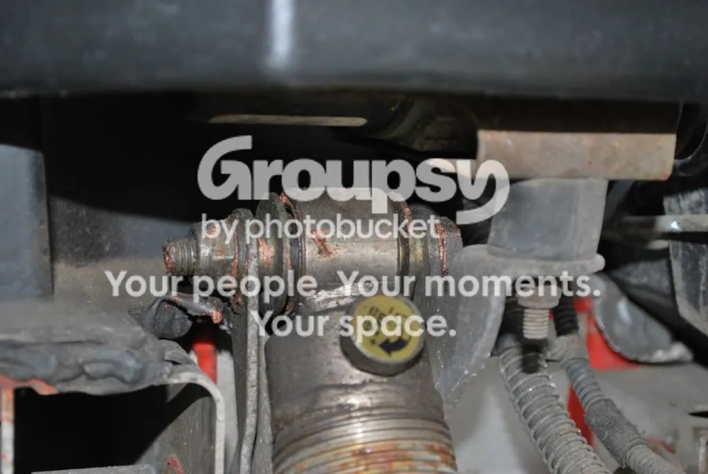 The top mount of a front shock in its chassis bracket, with a yellow cap on the shock and a nut on the bolt