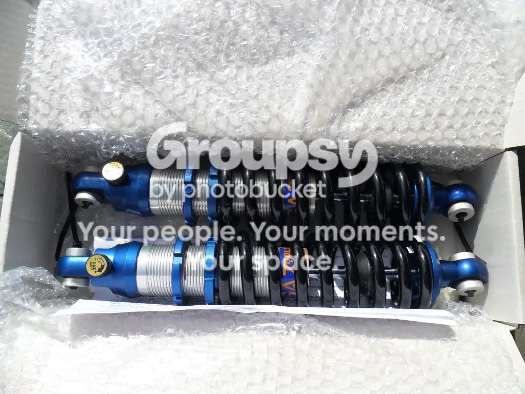Two new blue and silver coilover shocks in a cardboard box with bubble wrap