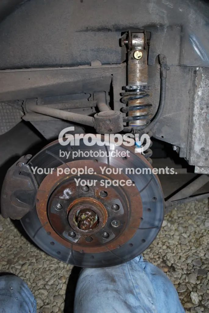 The rear hub and disc supported with a knee, with the old shock and spring still in place above