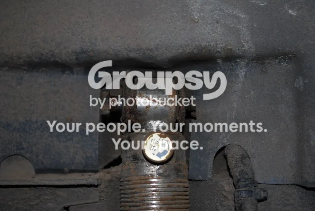 The rear shock top mount seen from underneath, with a yellow cap on the shock body