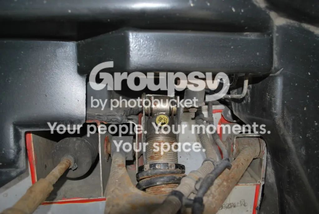 The front shock hanging free in the wheel arch after the top bolt is out