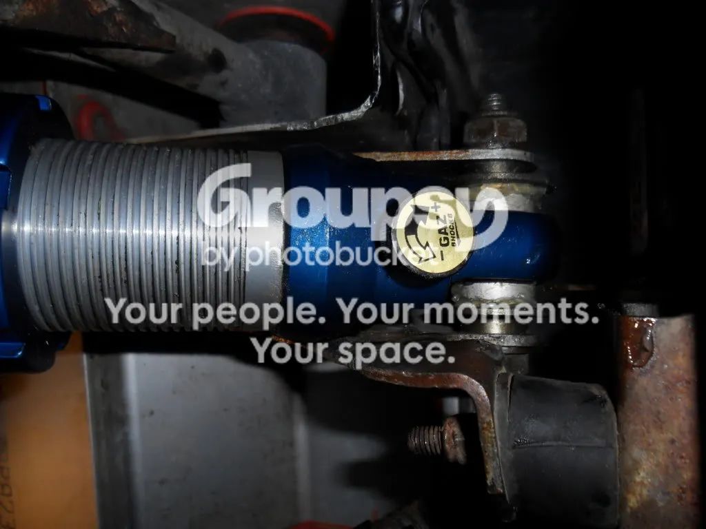 The top of a new blue shock in its bracket with the original spacers fitted, and the silver threaded body above
